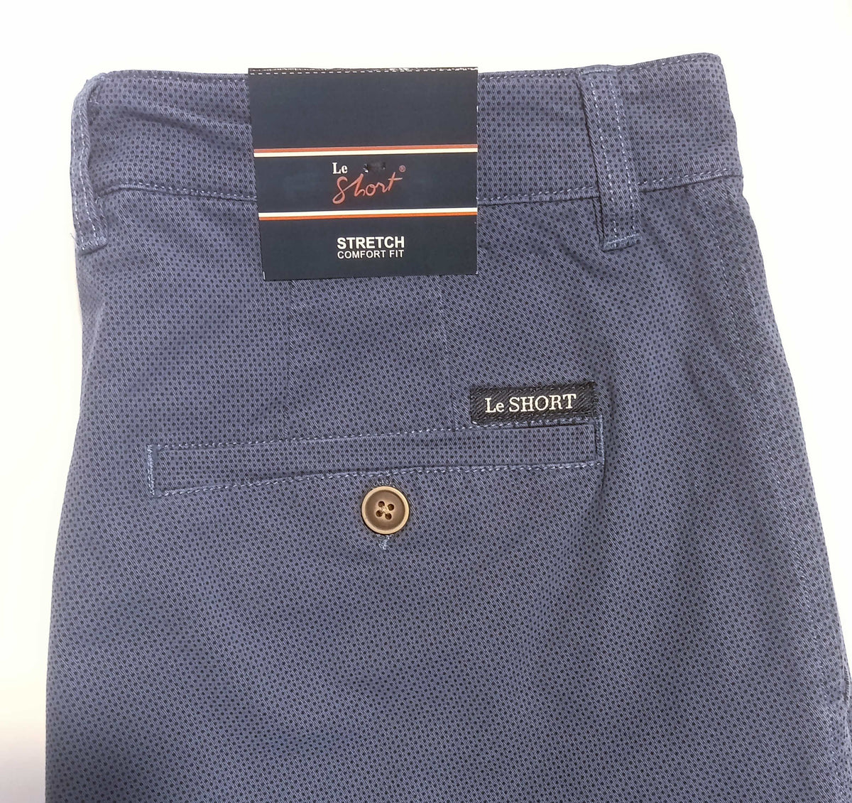 Close-up of the back waistband and pocket area of Le Short Stretch Comfort Trousers in a textured navy blue fabric, showing the brand labels and a brown button.