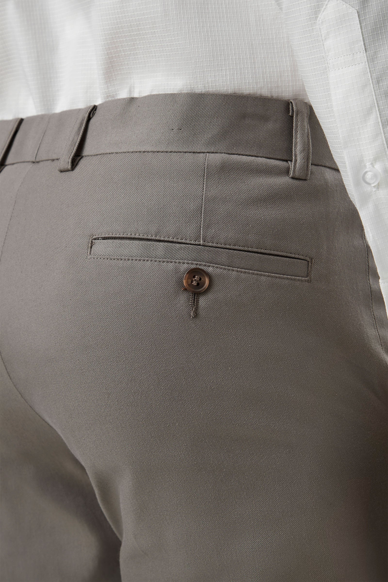 Close-up of gray pants with a button on a white background