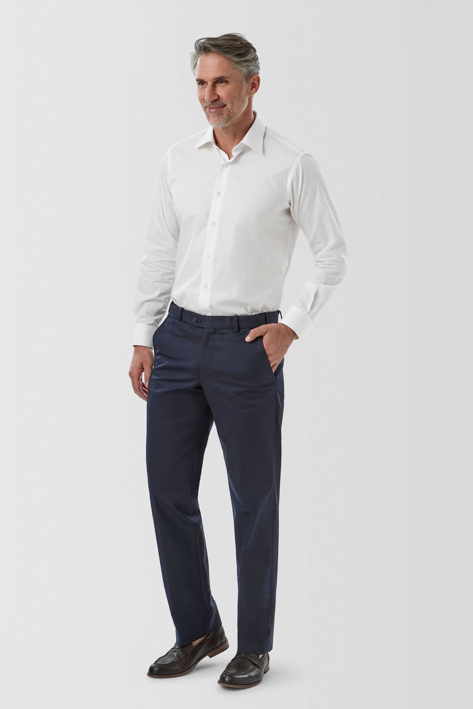 Man wearing a white dress shirt and navy pants on a white background