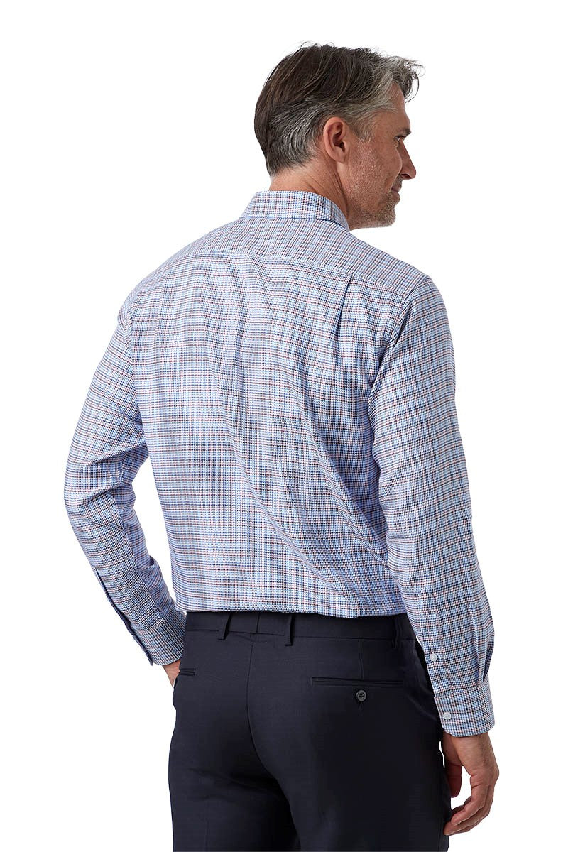 A man shown from the back wearing a light blue and white plaid long-sleeve dress shirt with dark trousers, photographed against a plain white background.