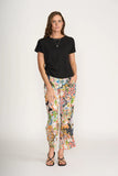 Woman wearing a black t-shirt and colorful patterned pants on a white background