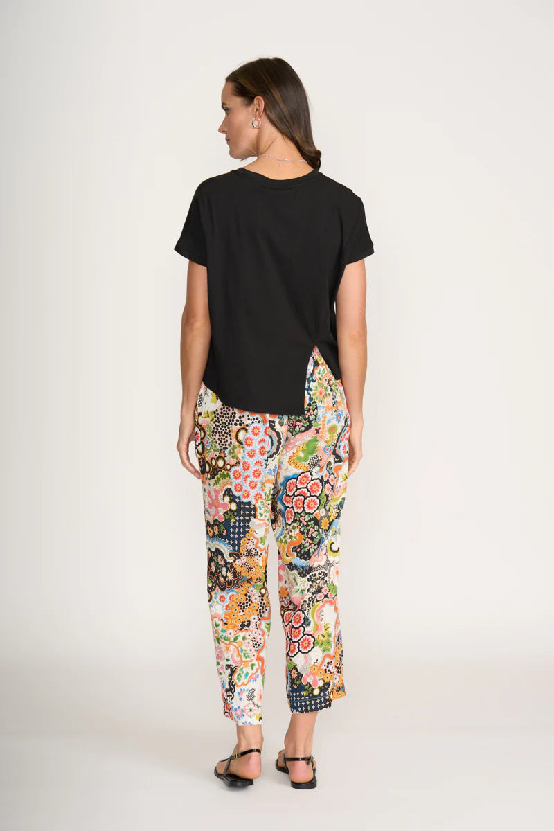 Woman wearing a black t-shirt and colorful floral pants on a white background