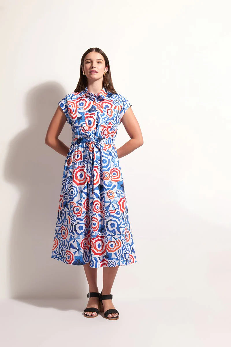 Woman wearing a colorful patterned dress against a plain background