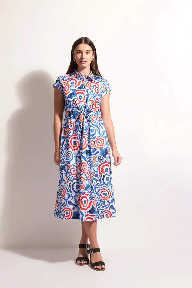 Woman wearing a colorful patterned dress against a plain background