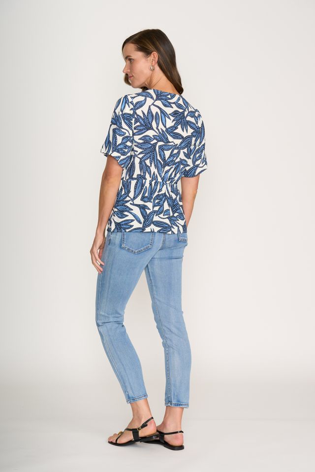 Woman wearing a blue and white patterned shirt and light blue jeans on a white background