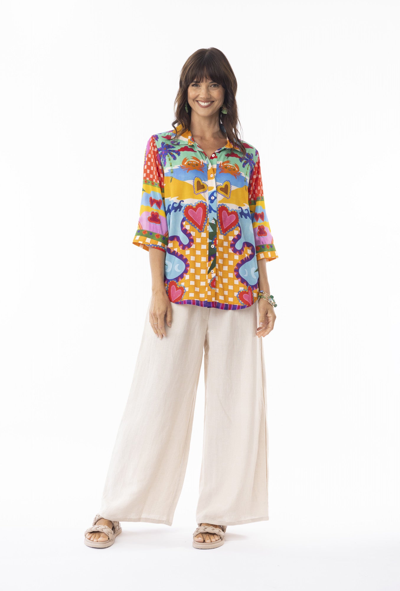 Woman wearing a colorful patterned shirt and white pants on a white background