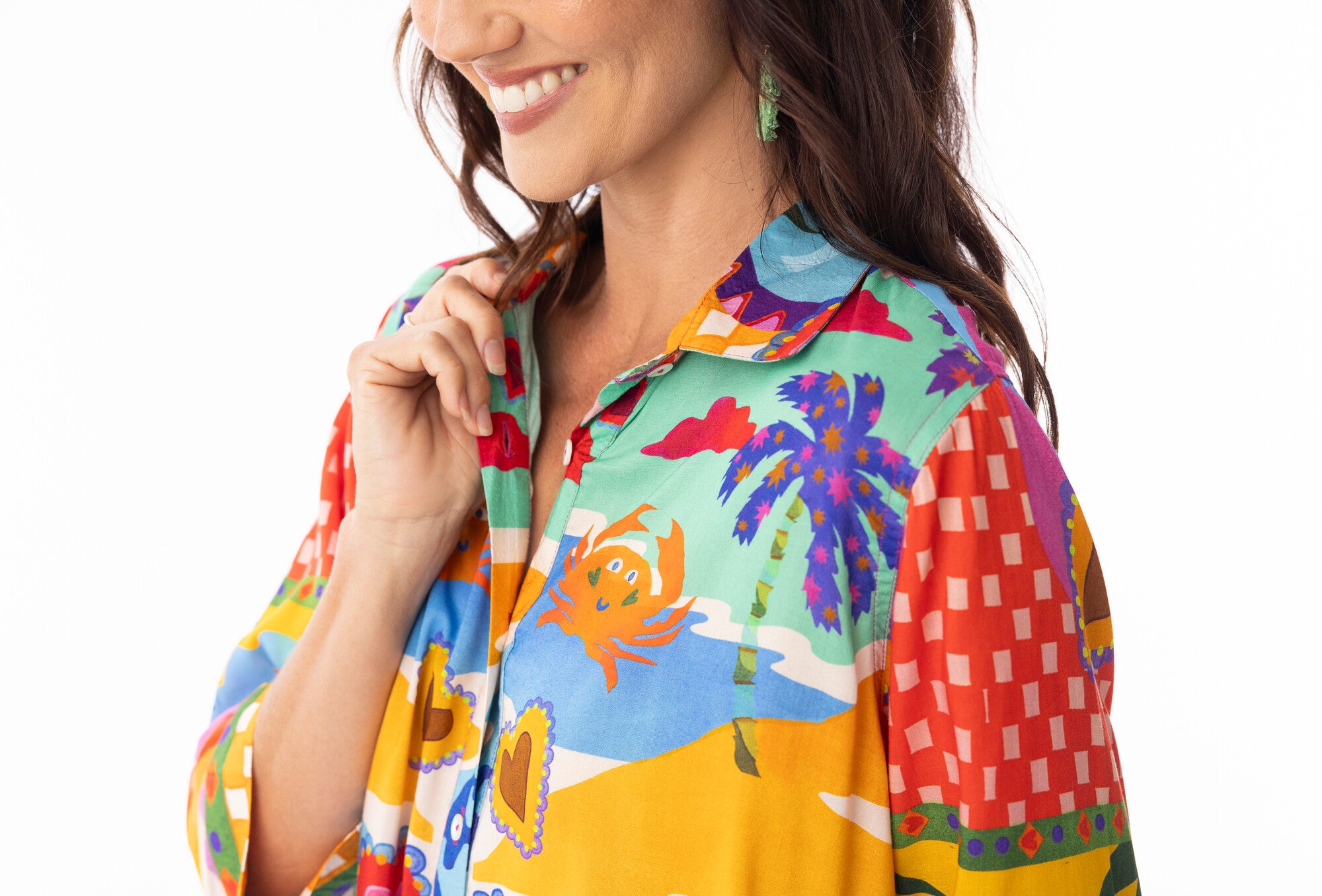 Woman wearing a colorful patterned shirt with palm trees and other designs.