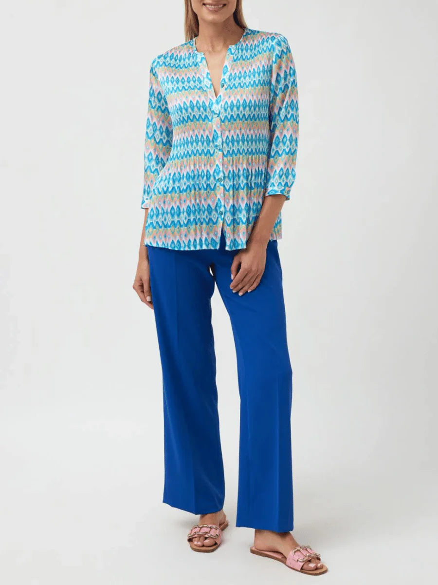 Woman wearing a blue and white patterned blouse with blue pants on a white background