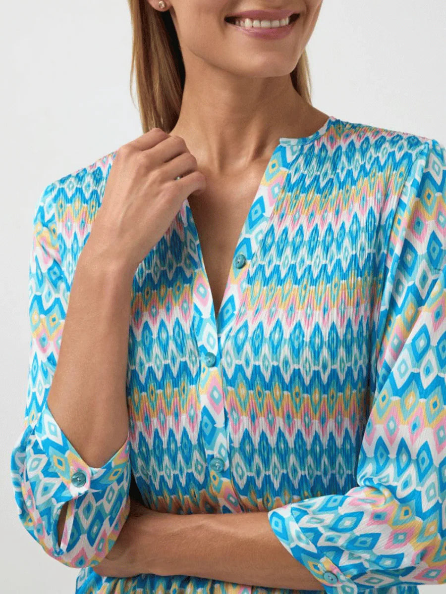 Woman wearing a colorful patterned blouse against a white background