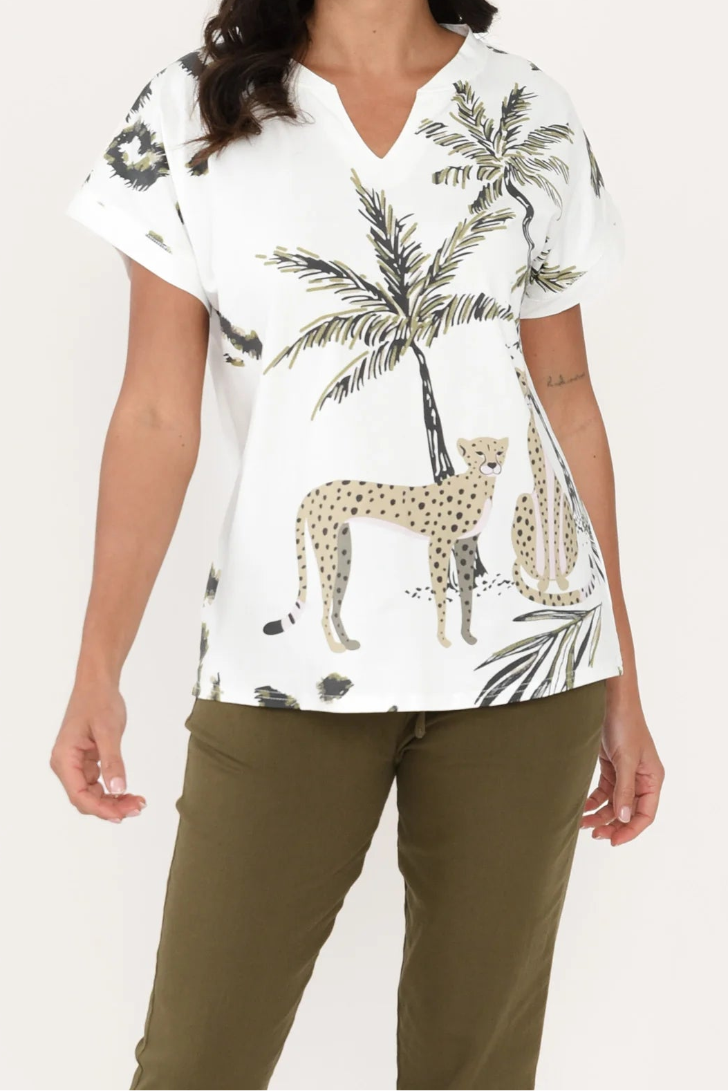 Woman wearing a white blouse with palm tree and leopard print on a plain background