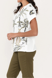 Woman wearing a white blouse with tropical leaf pattern and green pants on a white background