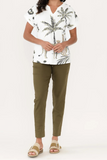 Person wearing a white shirt with palm tree design and green pants on a white background