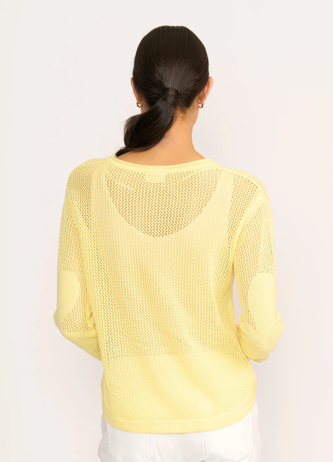 Person wearing a light yellow knitted sweater on a white background