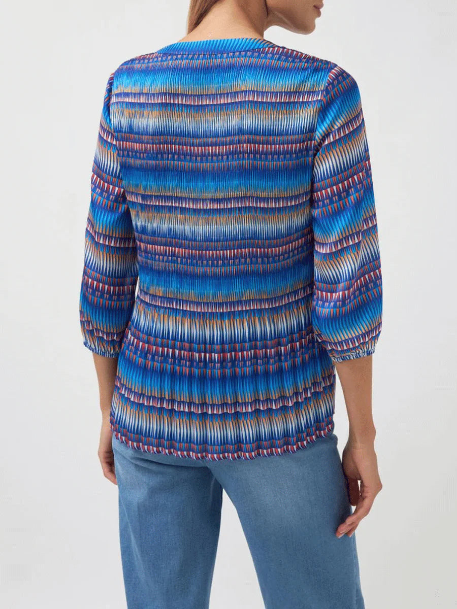 Person wearing a colorful striped shirt with a plain background