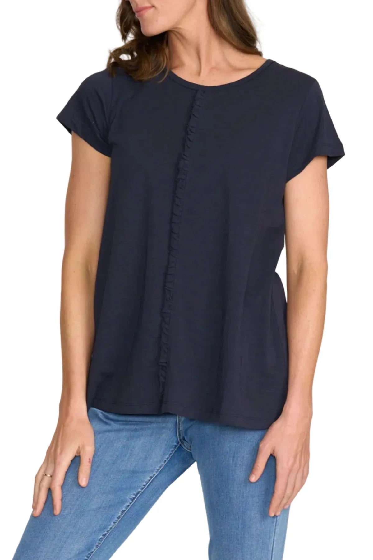 Woman wearing a navy blue top with a button detail and blue jeans on a white background