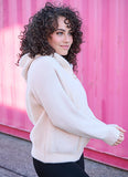 Woman wearing a cream-colored sweater in front of a pink background