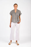 Woman wearing a gray patterned blouse and white pants on a white background