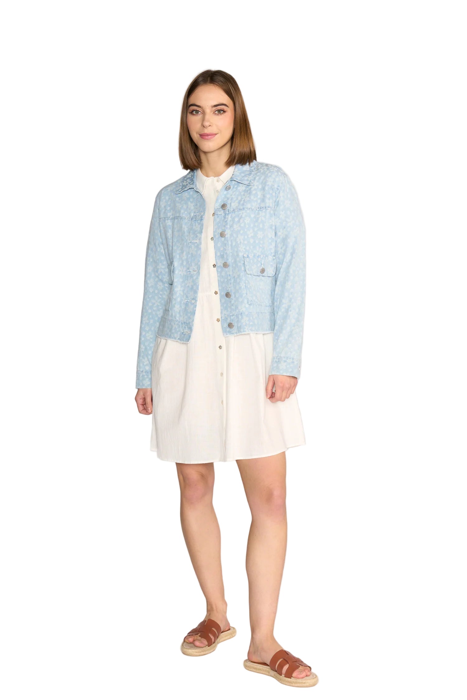 Woman wearing a light blue denim jacket over a white dress on a white background