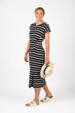 Woman wearing a black and white striped dress holding a hat on a white background
