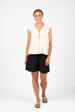 Woman wearing a white blouse and black shorts on a white background