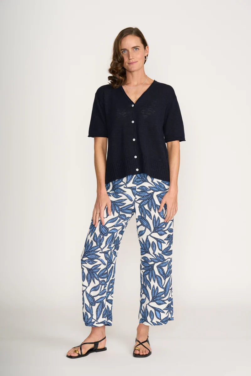 Woman wearing a black top and blue leaf-patterned pants on a white background