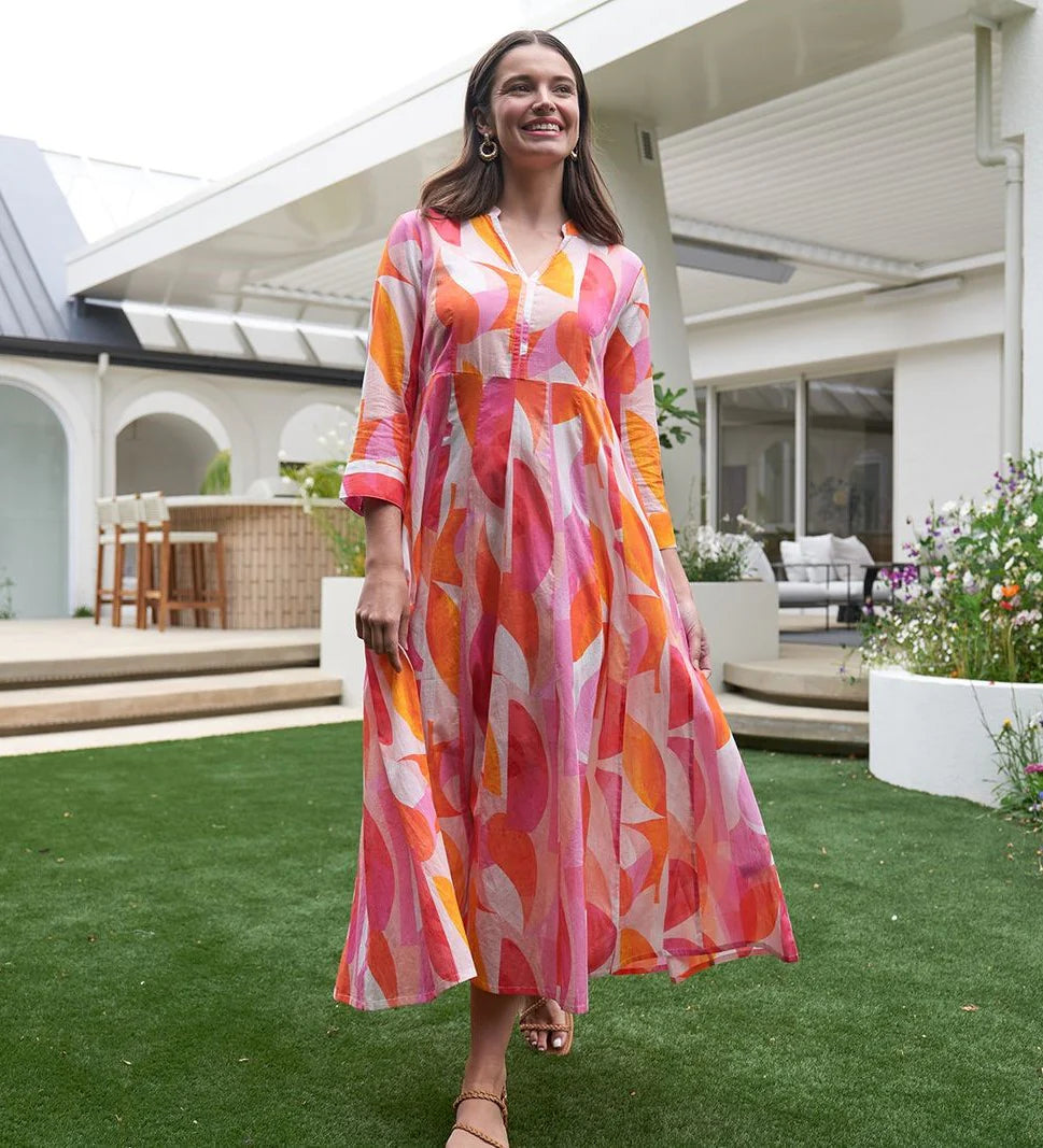 Woman in a colorful dress standing on grass with a modern house in the background