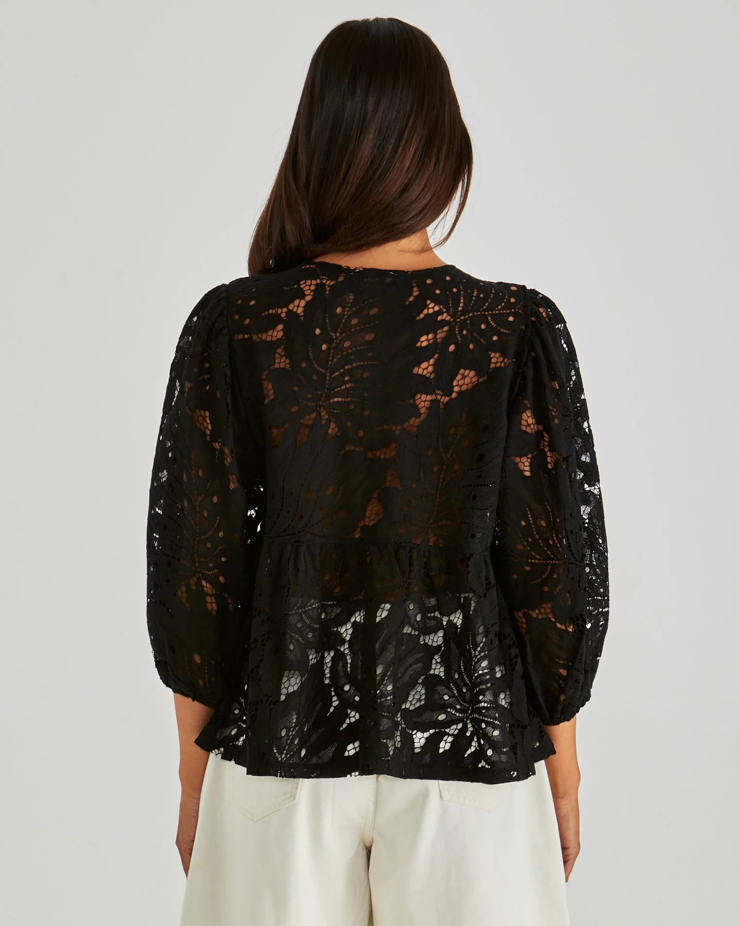 Black lace top worn by a person on a plain background
