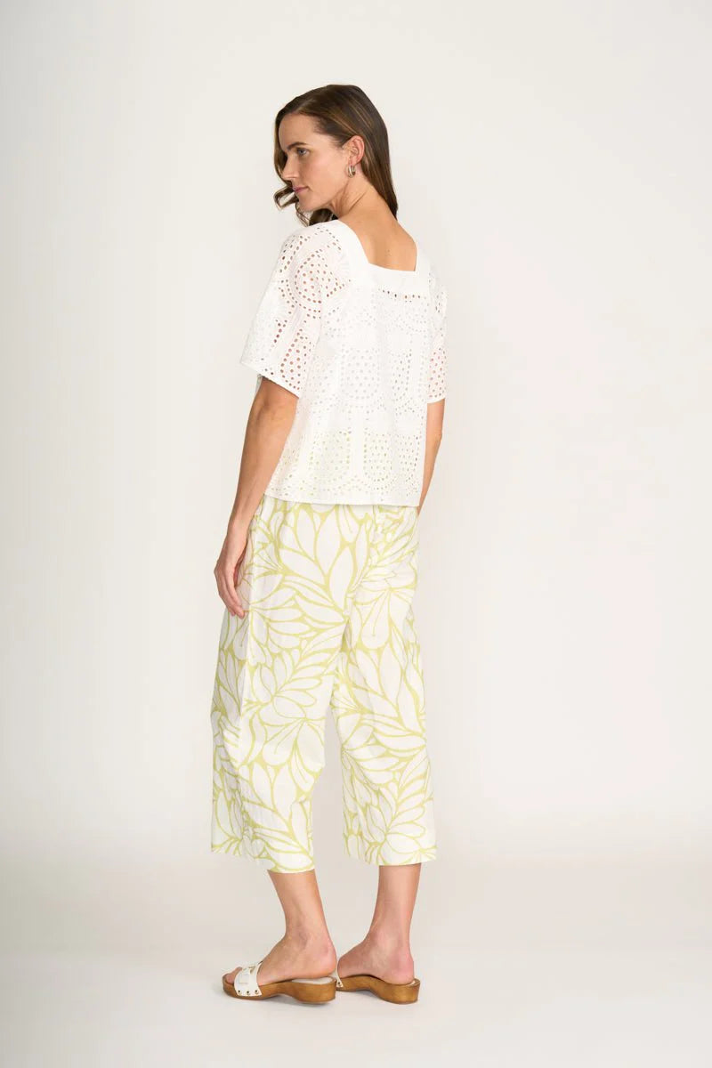 Woman wearing a white top and yellow patterned pants on a white background