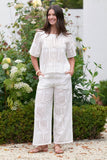 Woman wearing a white lace outfit standing in a garden.