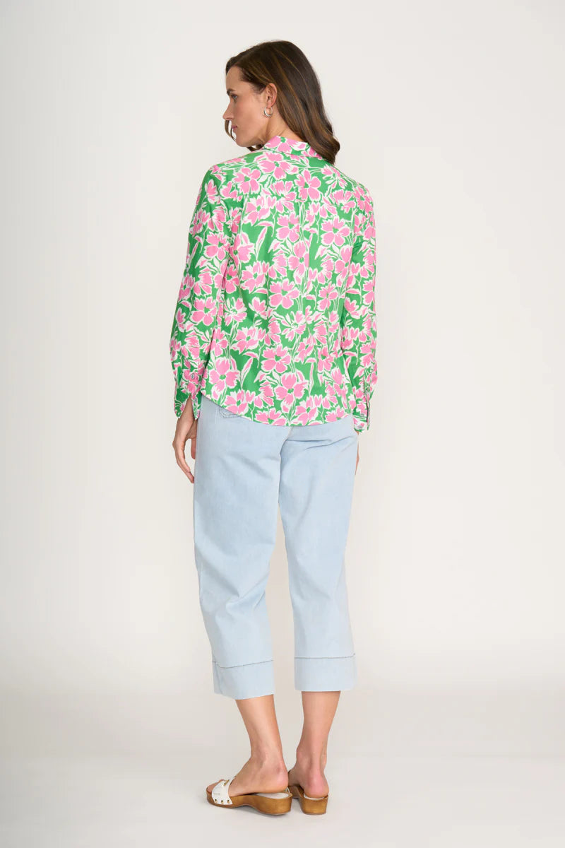 Woman wearing a floral blouse and light blue pants on a white background