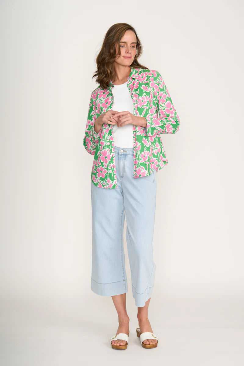 Woman wearing a floral jacket, white shirt, and light blue jeans on a white background