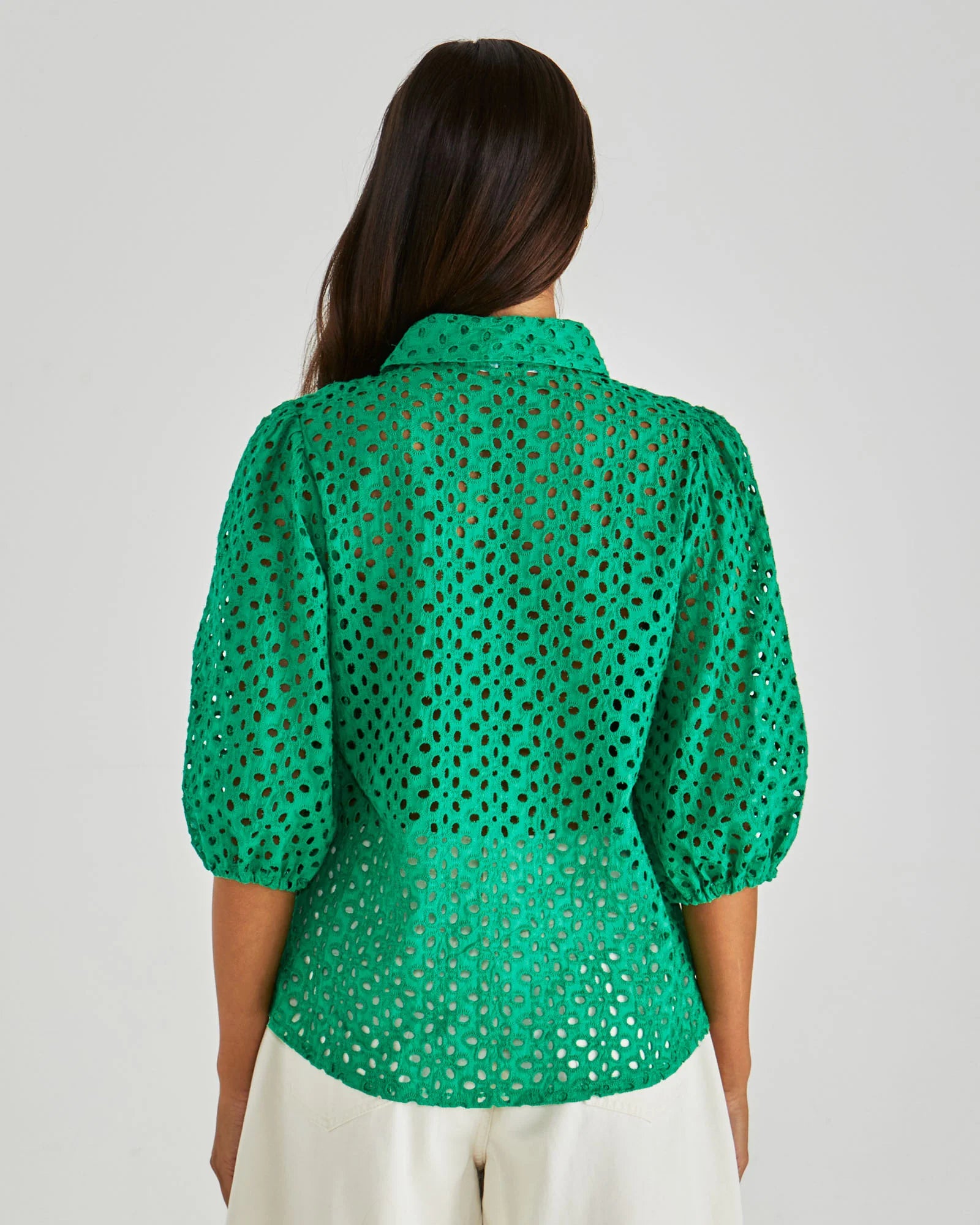 Green polka dot blouse worn by a person on a plain background