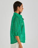Woman wearing a green crochet top against a plain background