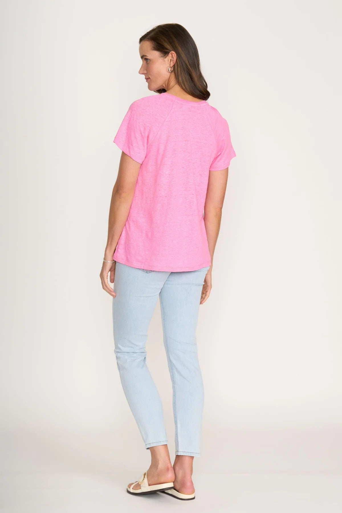 Woman wearing a pink t-shirt and light blue jeans on a white background