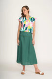 Woman wearing a colorful top and green skirt on a white background
