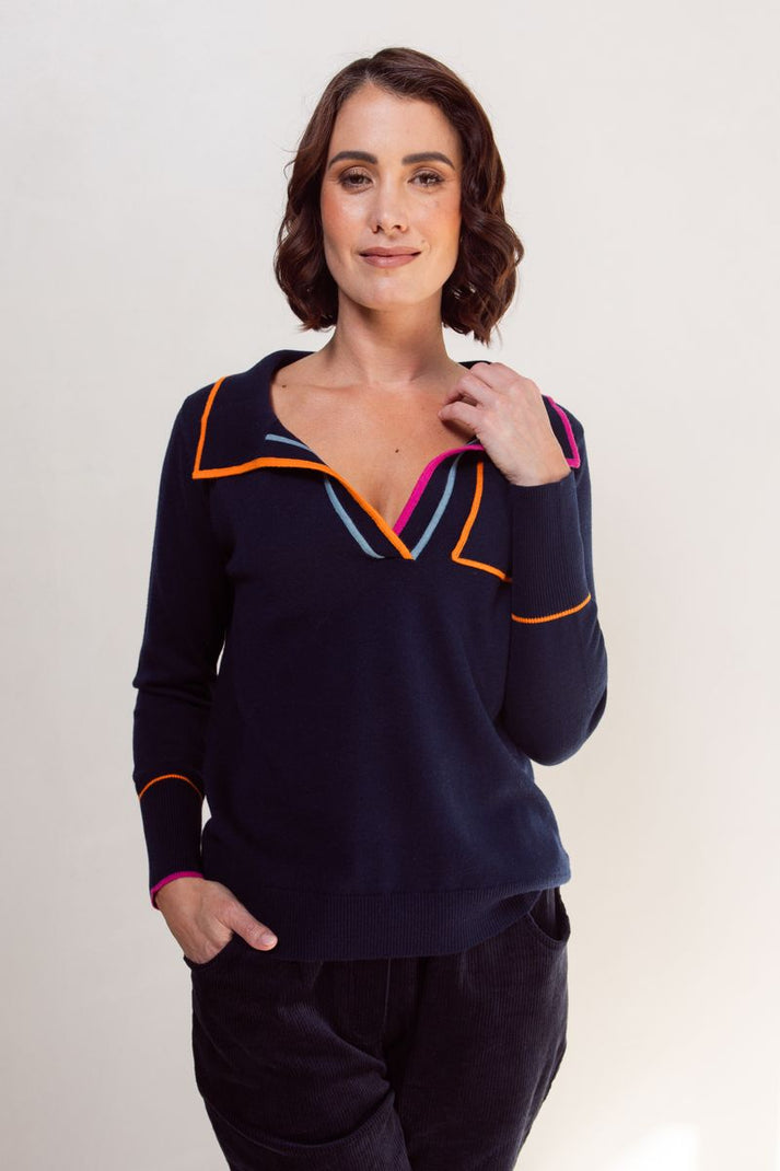 Woman wearing a navy blue top with colorful trim on a white background