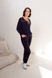Woman wearing a navy blue outfit with orange accents in a minimalistic room.