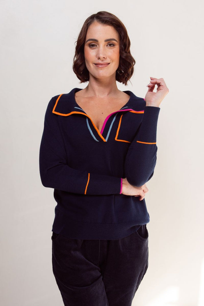 Woman wearing a navy blue outfit with colorful accents on a plain background