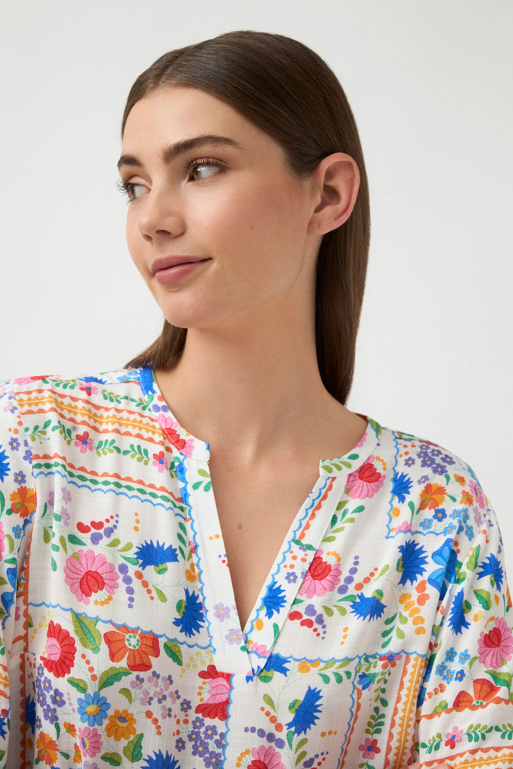 Woman wearing a colorful floral blouse against a white background