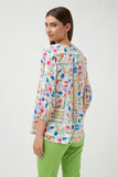 Woman wearing a colorful floral blouse and green pants on a white background