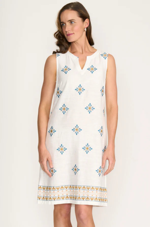 Woman wearing a white dress with blue floral patterns on a plain background
