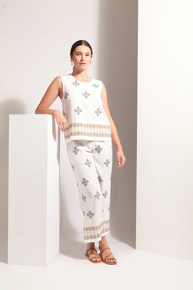 Woman wearing a white outfit with floral patterns in a minimalistic setting
