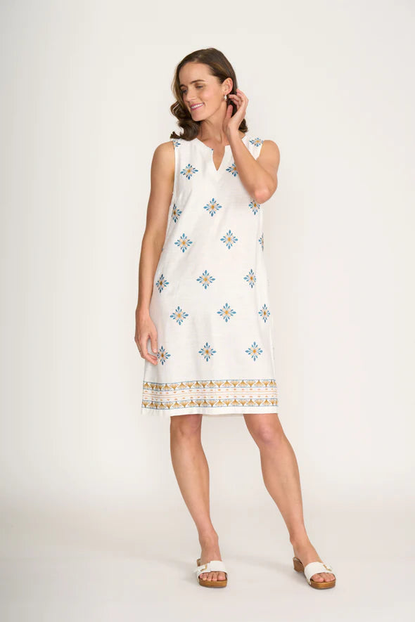 Woman wearing a white dress with colorful patterns on a plain background