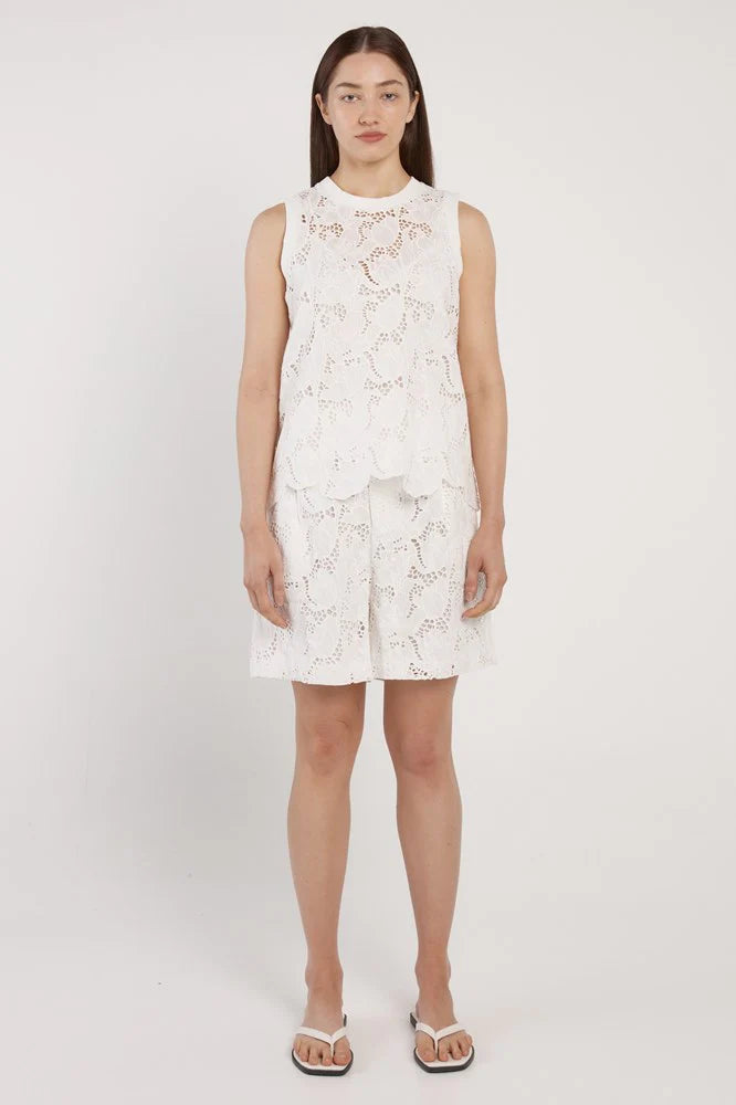 Woman wearing a white floral dress on a plain background