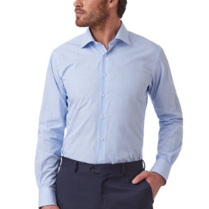 A man wearing a light blue long-sleeve dress shirt and dark navy trousers, standing against a plain white background.