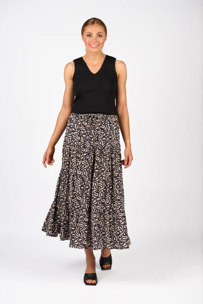 Woman wearing a black sleeveless top and patterned skirt on a white background