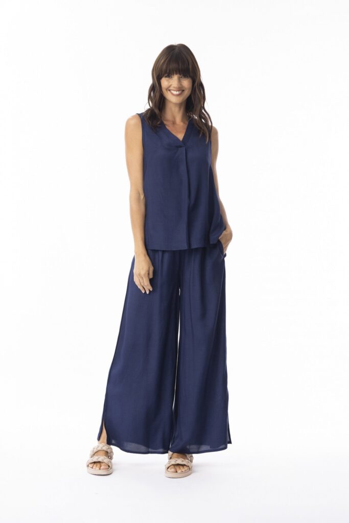 Woman wearing a navy blue sleeveless top and wide-leg pants on a white background